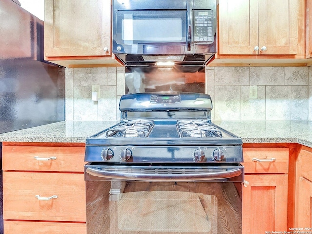 kitchen featuring light stone countertops, tasteful backsplash, and black appliances