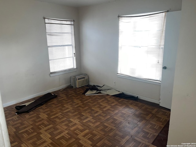 empty room featuring dark parquet flooring and a wall mounted AC