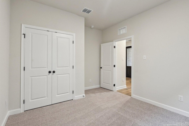 unfurnished bedroom featuring light carpet and a closet