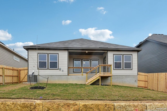 rear view of property with central AC unit and a yard