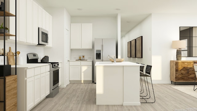 kitchen with white cabinets, a breakfast bar area, light hardwood / wood-style flooring, an island with sink, and stainless steel appliances