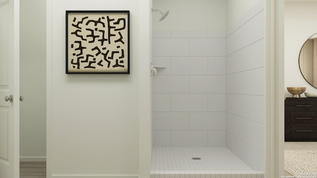 bathroom with a tile shower and hardwood / wood-style flooring