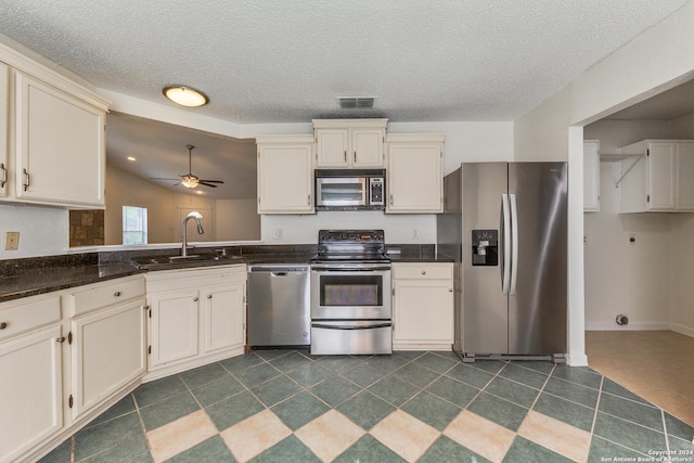 kitchen featuring ceiling fan, sink, vaulted ceiling, dark tile patterned flooring, and appliances with stainless steel finishes