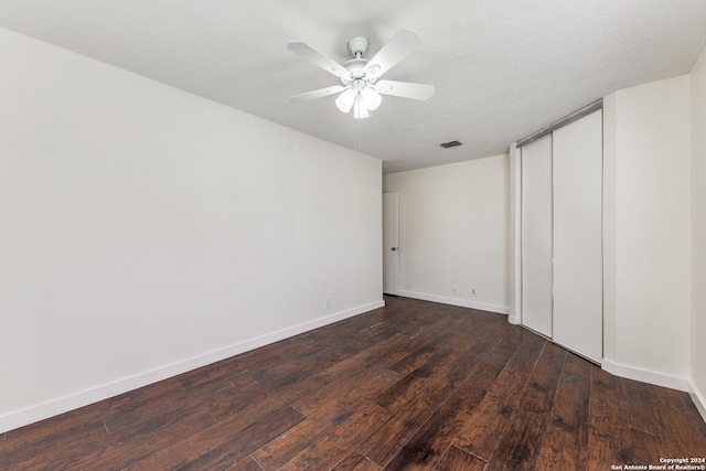 unfurnished room featuring a textured ceiling, ceiling fan, and dark wood-type flooring