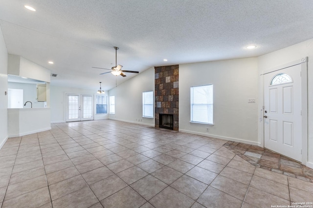 unfurnished living room featuring ceiling fan, light tile patterned floors, a wealth of natural light, and vaulted ceiling