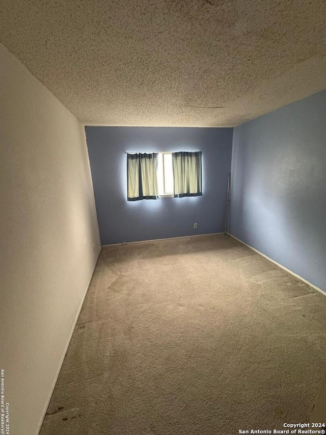 carpeted empty room featuring a textured ceiling