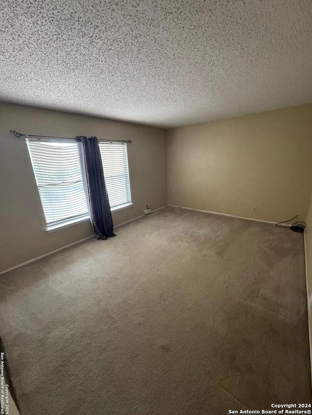 carpeted empty room featuring a textured ceiling