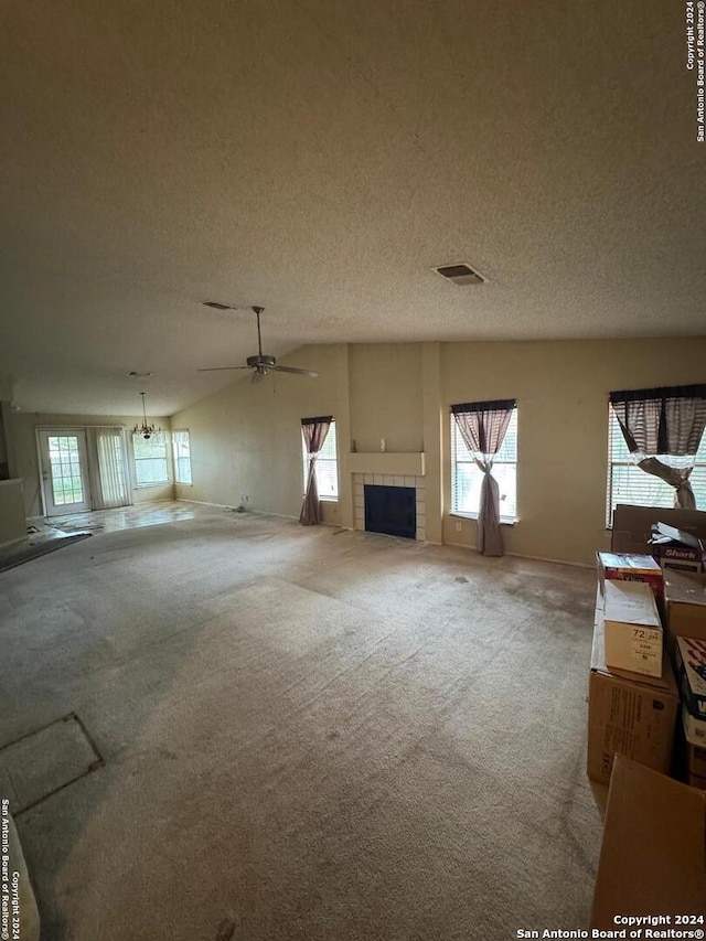 unfurnished living room featuring carpet flooring, a tile fireplace, ceiling fan, and a textured ceiling