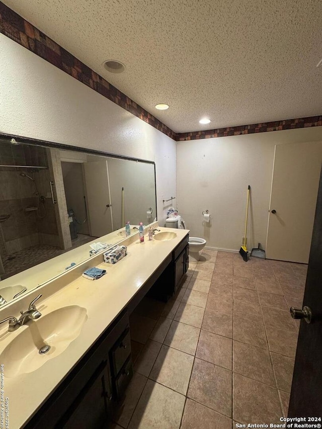 bathroom with toilet, vanity, a textured ceiling, and tile patterned floors