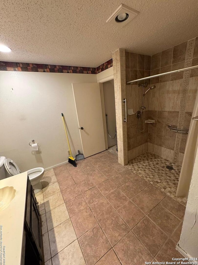 bathroom with a tile shower, tile patterned floors, vanity, and a textured ceiling