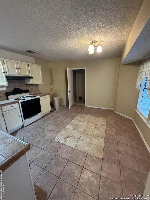 kitchen with tile countertops, white cabinets, white range, a textured ceiling, and light tile patterned flooring