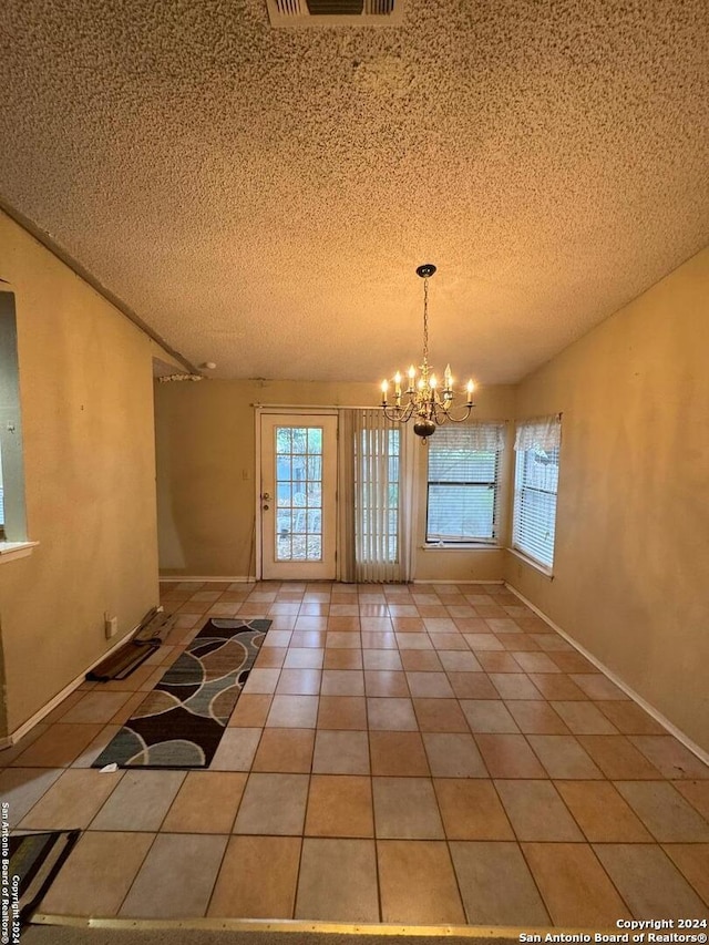 unfurnished dining area featuring tile patterned flooring, a notable chandelier, and a textured ceiling