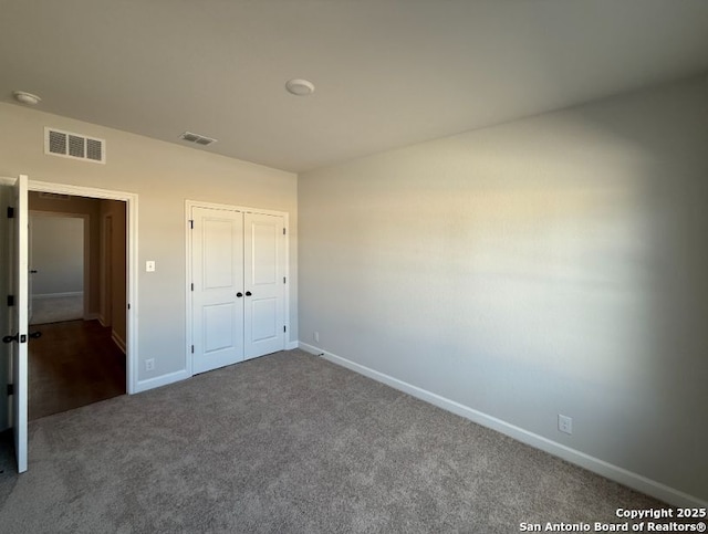 unfurnished bedroom with a closet and dark colored carpet