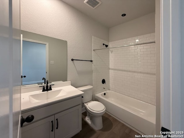 full bathroom with toilet, tiled shower / bath, vanity, and hardwood / wood-style flooring