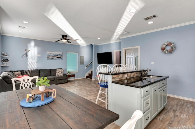 kitchen with a kitchen breakfast bar, ornamental molding, sink, a center island, and light hardwood / wood-style floors