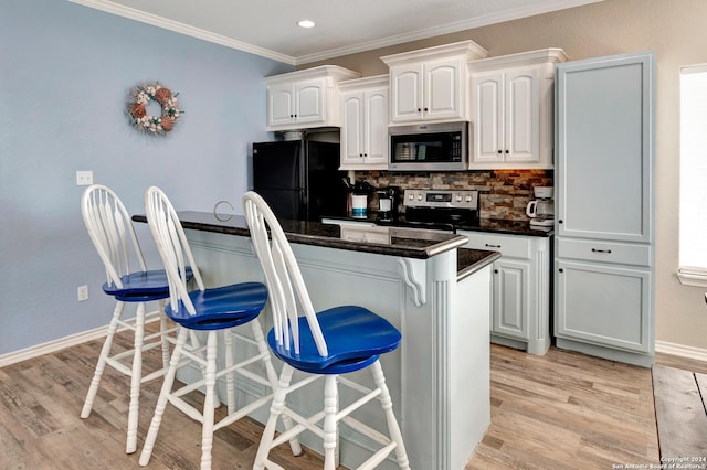 kitchen with a kitchen breakfast bar, stainless steel appliances, white cabinetry, and light hardwood / wood-style floors