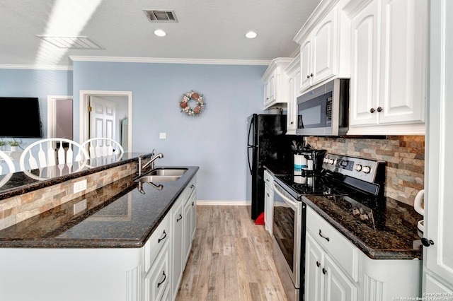 kitchen featuring sink, dark stone countertops, appliances with stainless steel finishes, white cabinets, and light wood-type flooring