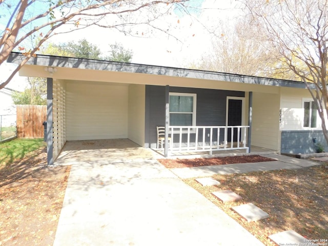 ranch-style home featuring covered porch and a carport