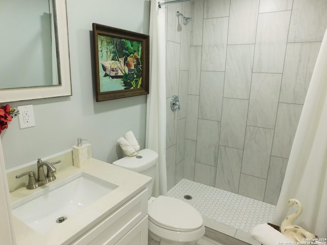 bathroom with vanity, toilet, and tiled shower