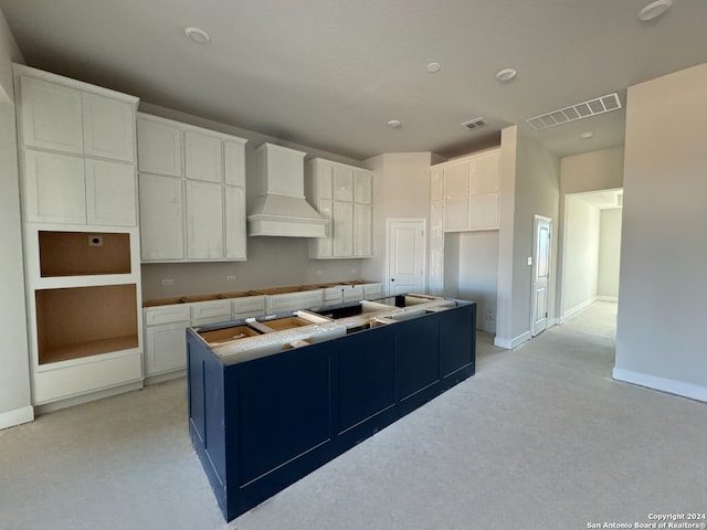 kitchen with white cabinetry, a kitchen island, and custom exhaust hood