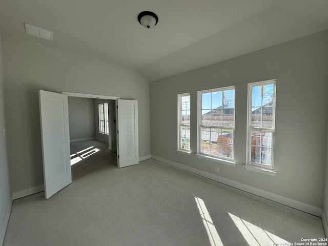 unfurnished bedroom with light colored carpet and lofted ceiling