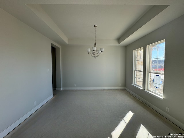 spare room featuring a notable chandelier and a raised ceiling