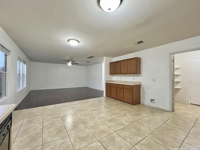 kitchen featuring ceiling fan, dishwasher, a textured ceiling, and light hardwood / wood-style flooring