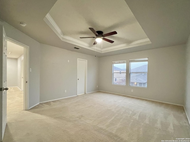 carpeted spare room featuring a tray ceiling, ceiling fan, and ornamental molding