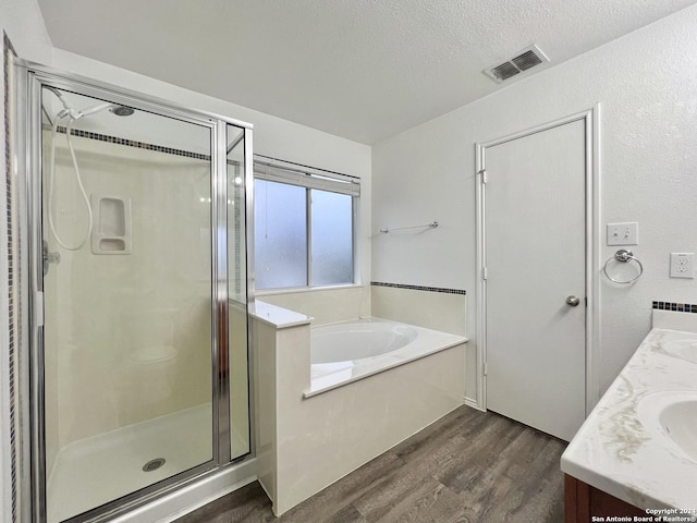 bathroom with hardwood / wood-style floors, vanity, a textured ceiling, and independent shower and bath