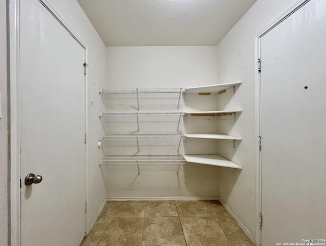 walk in closet with light tile patterned floors