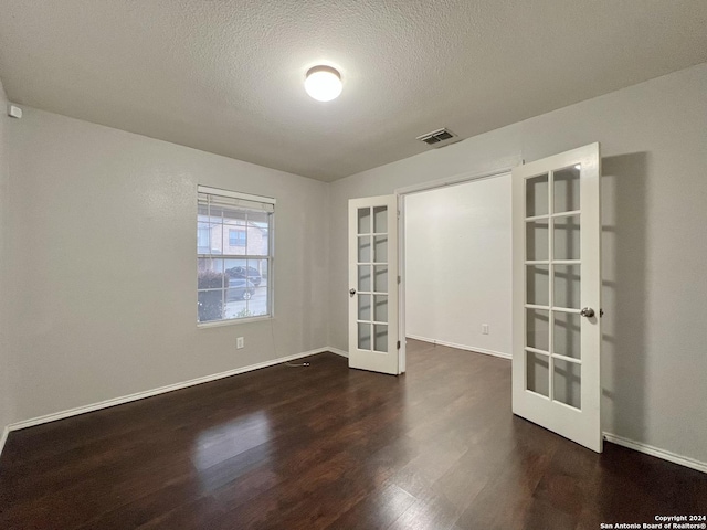 unfurnished room with dark hardwood / wood-style flooring, a textured ceiling, and french doors