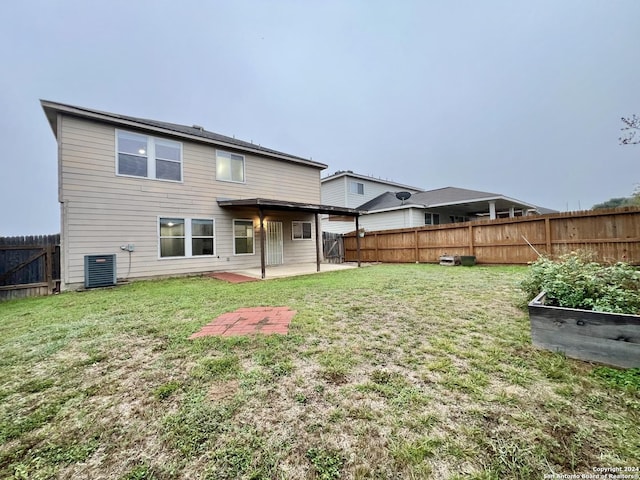 rear view of house with a lawn, a patio, and central AC