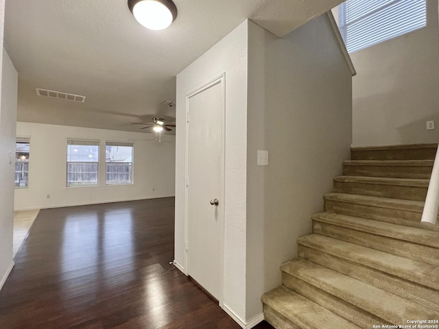 staircase with hardwood / wood-style flooring, ceiling fan, and a textured ceiling