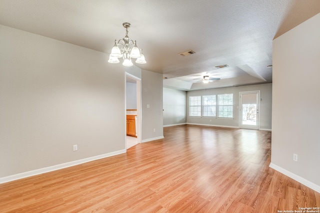 spare room featuring ceiling fan with notable chandelier, a textured ceiling, and light hardwood / wood-style flooring