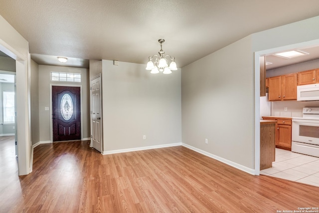 entryway with a chandelier, a textured ceiling, and light wood-type flooring