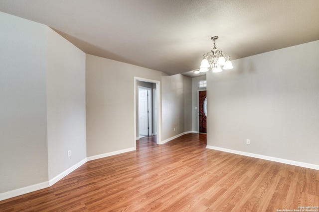 unfurnished room with a notable chandelier and light wood-type flooring