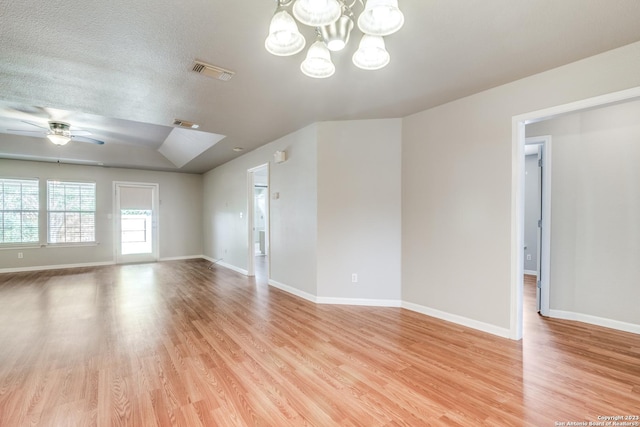 unfurnished room with ceiling fan with notable chandelier, a textured ceiling, and light hardwood / wood-style flooring