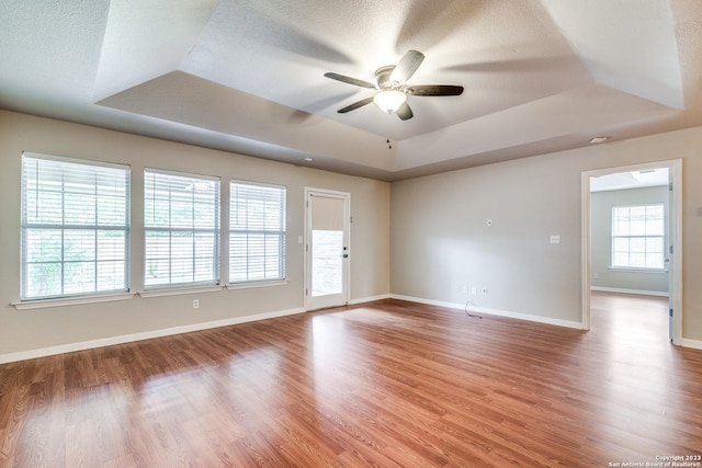 spare room with a raised ceiling, ceiling fan, and wood-type flooring