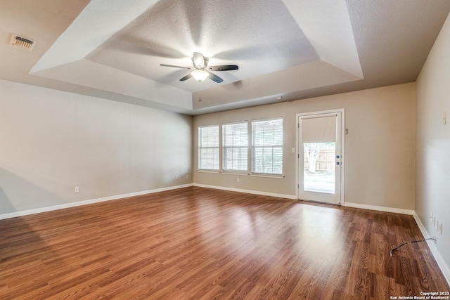 unfurnished room featuring wood-type flooring, a textured ceiling, a raised ceiling, and ceiling fan