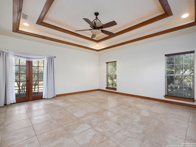 empty room with ceiling fan, french doors, a tray ceiling, light tile patterned floors, and ornamental molding