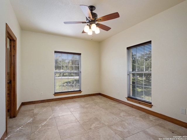 tiled spare room with ceiling fan