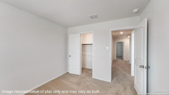 unfurnished bedroom featuring a walk in closet, light carpet, and a closet