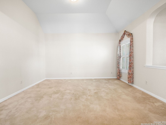 carpeted spare room featuring vaulted ceiling