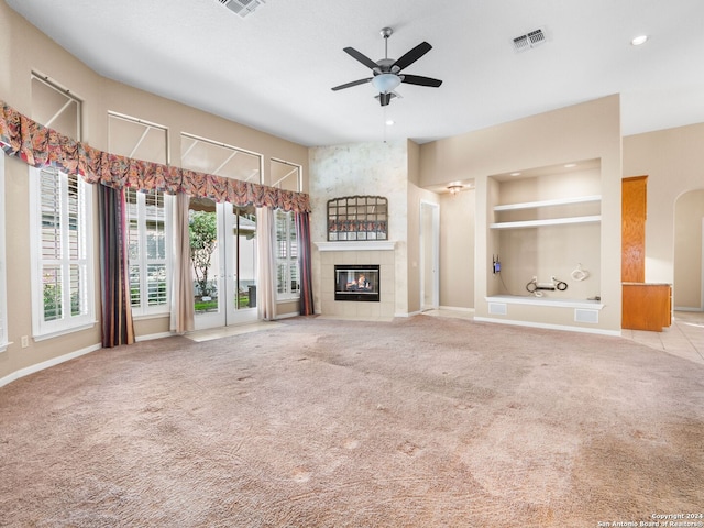 unfurnished living room featuring a tile fireplace, light colored carpet, and ceiling fan