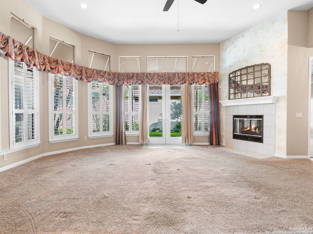 unfurnished living room featuring carpet flooring, a tile fireplace, ceiling fan, and plenty of natural light