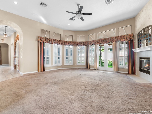 unfurnished living room featuring ceiling fan, a fireplace, and light carpet