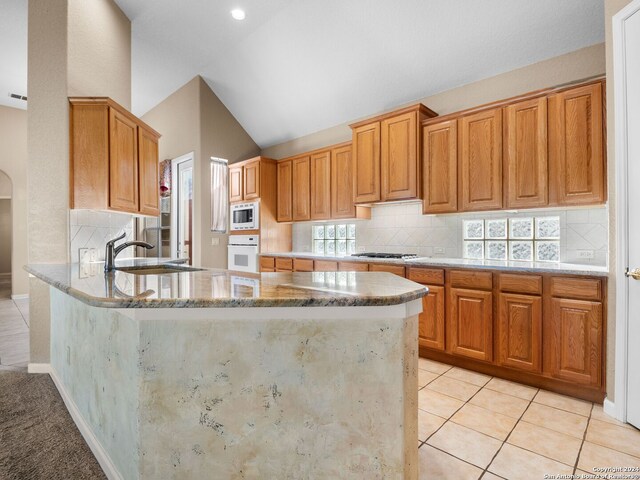 kitchen featuring light stone countertops, light tile patterned floors, white appliances, and vaulted ceiling