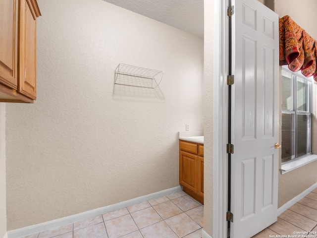 laundry area featuring light tile patterned floors and a textured ceiling