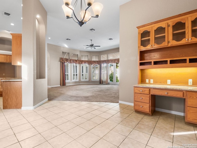 unfurnished office with ceiling fan with notable chandelier, light colored carpet, and built in desk