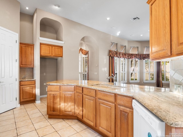 kitchen with sink, a kitchen island, light stone counters, white dishwasher, and light tile patterned flooring